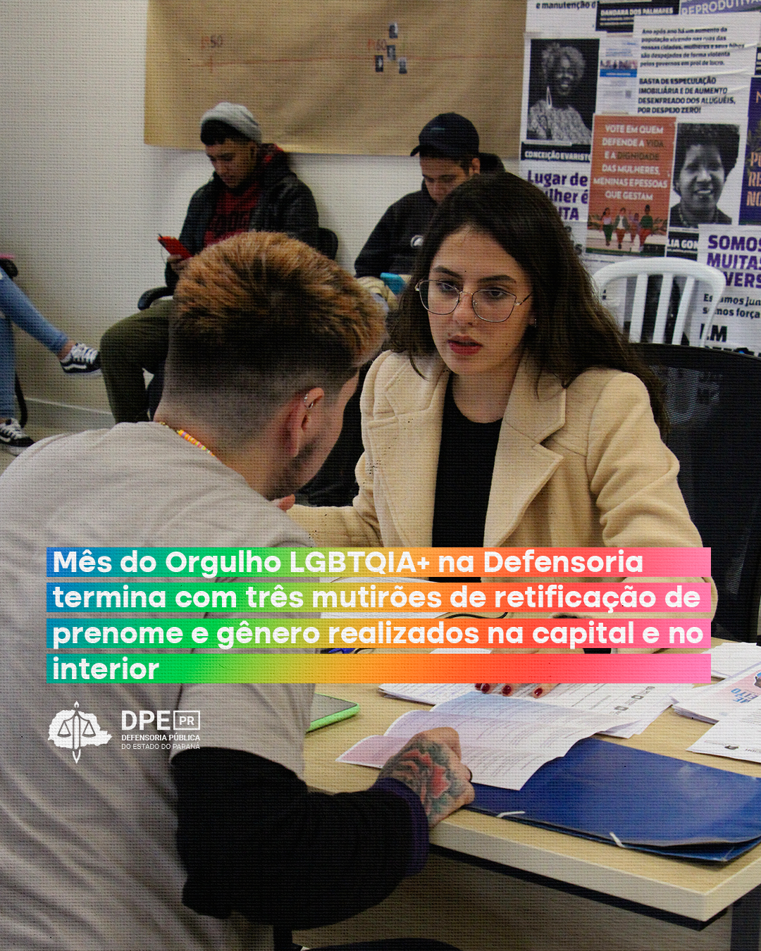 Imagem que mostra um atendimento no mutirão de Curitiba. A pessoa que está sendo atendida ouve a explicação de uma atendente da Defensoria, que mostra para ela uma cartilha que está sobre uma mesa. Também é possível ler o título da matéria: “Mês do Orgulho LGBTQIA+ na Defensoria termina com três mutirões de retificação de prenome e gênero realizados na capital e no interior”, que está escrito em letras brancas sobre um fundo multicolorido, com as cores do arco-íris. Abaixo, está o logo da Defensoria.