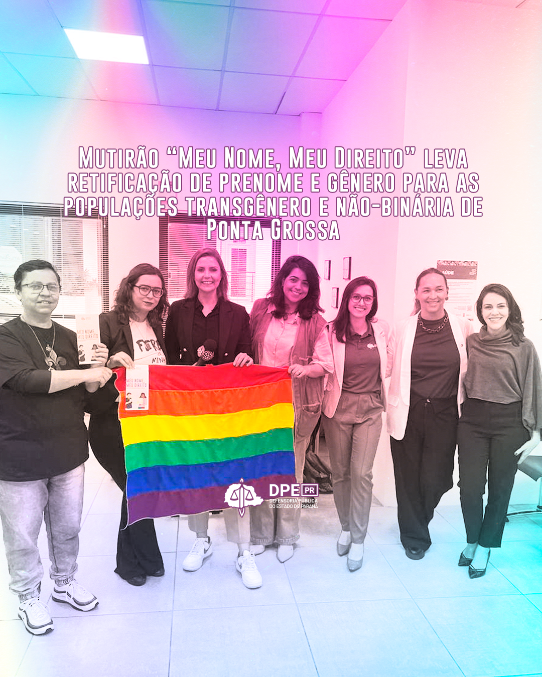 Imagem que mostra diversas pessoas da equipe que trabalhou no mutirão segurando uma bandeira LGBT com as cores do arco-íris. Acima das pessoas, está escrito o título da matéria “Mutirão Meu Nome, Meu Direito leva retificação de prenome e gênero para as populações transgênero e não-binária de Ponta Grossa”.