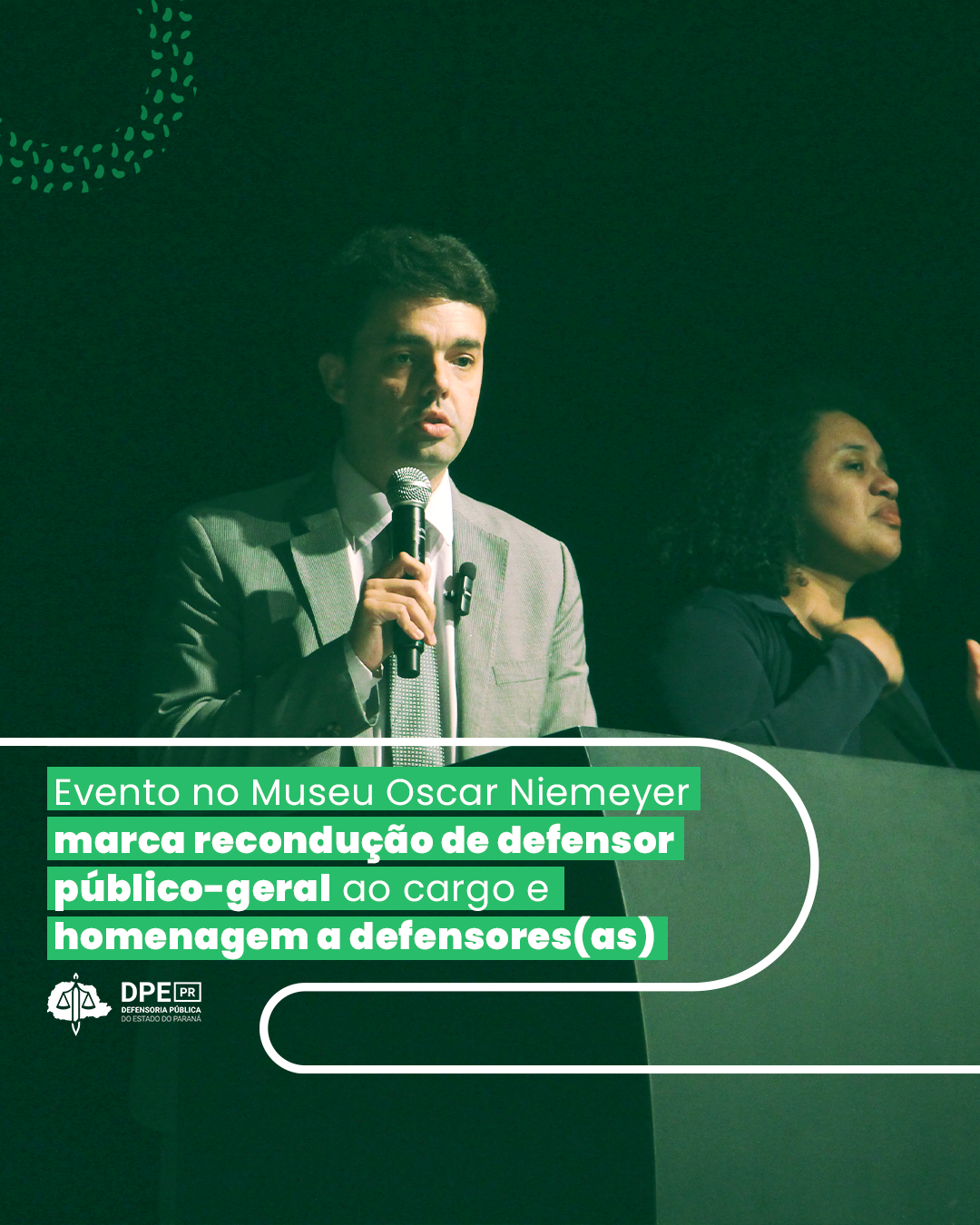 Imagem que mostra o defensor-geral André Giamberardino discursando no evento de sua recondução ao cargo. Acima da imagem está escrito o título da matéria.