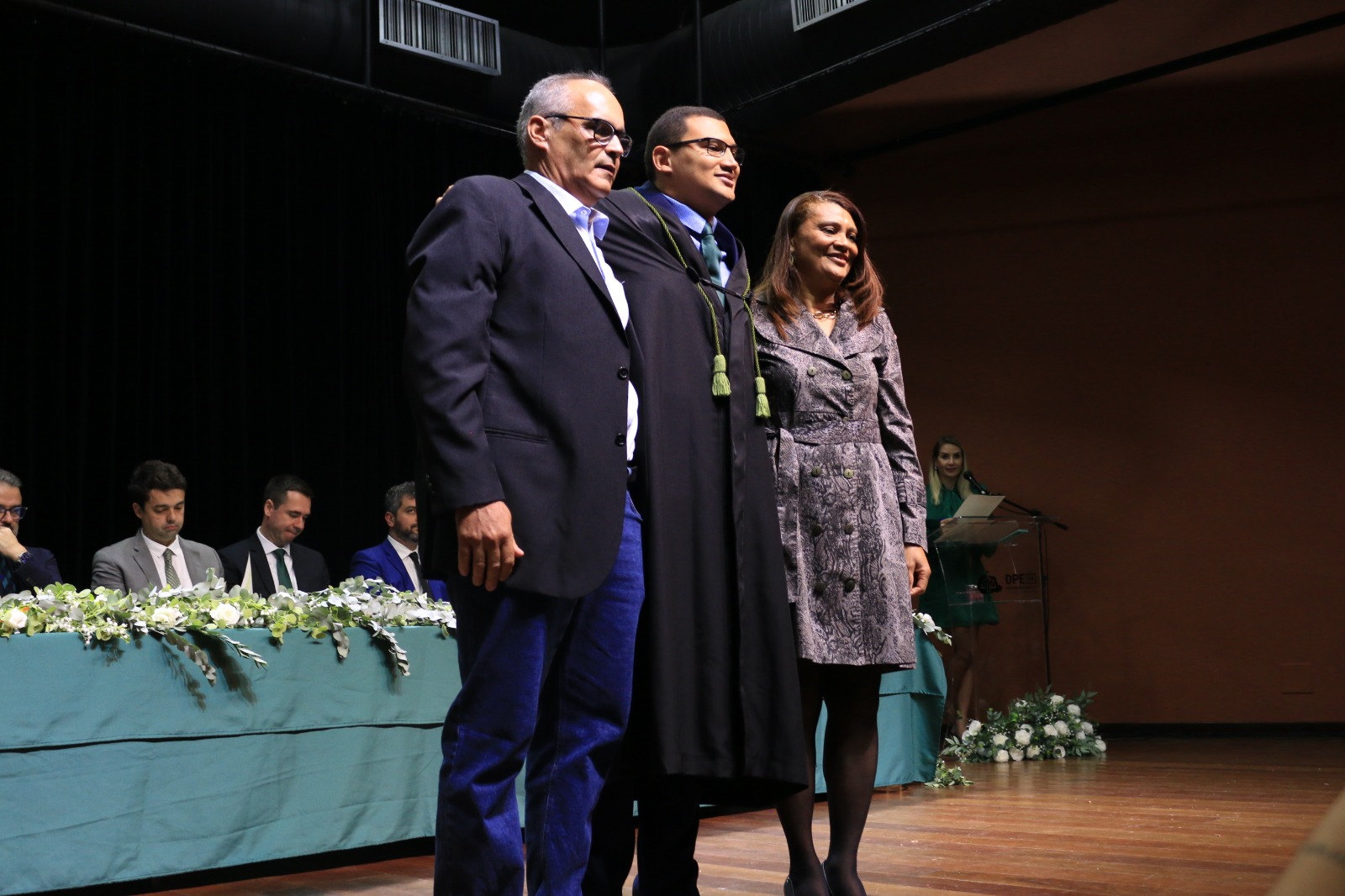 Imagem que mostra o defensor público Rafael Guimarães recém empossado, ao lado dos pais, posando para fotos, em cerimônia realizada nesta quinta-feira (18), em Curitiba.