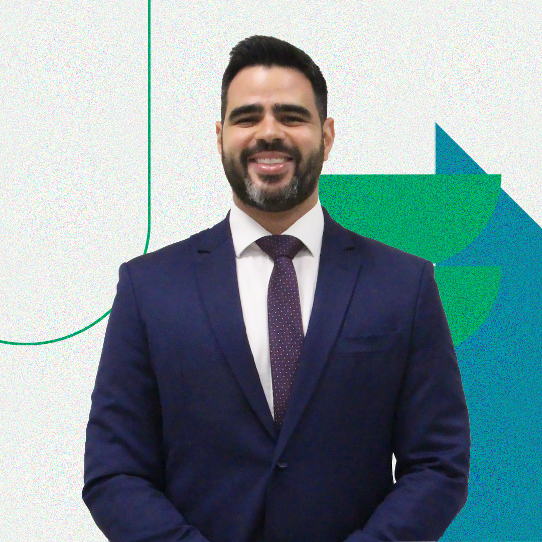 Imagem com a foto do Chefe de Gabinete, Pedro Martins. Ele é um homem branco, alto e usa um terno azul escuro com uma grava de mesmo tom.
