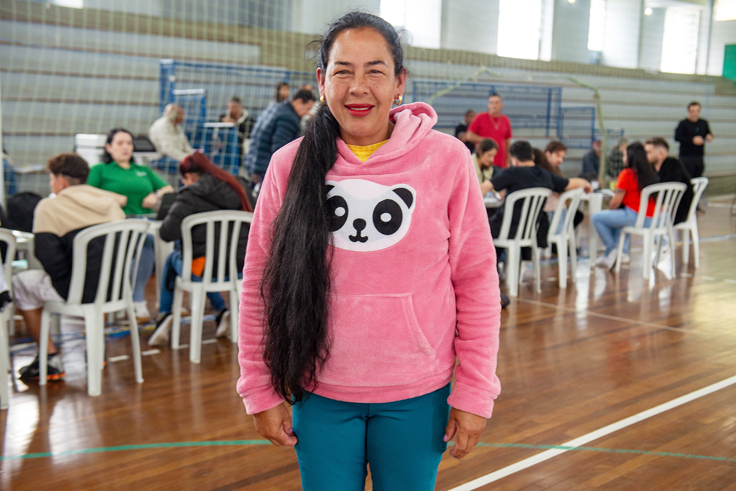 Imagem colorida horizontal em que se vê uma mulher de moleton e jeans posando ao centro.