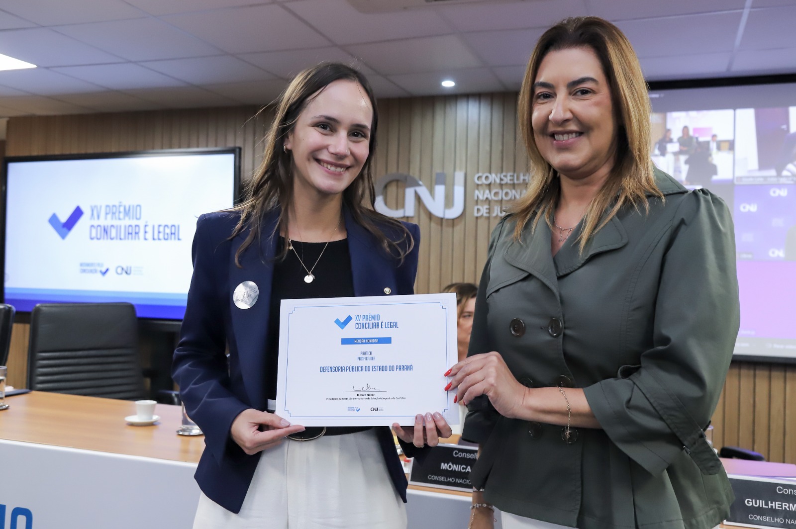 A Primeira Sub-Defensora Geral do Estado Livia recebe congratulações de uma representante do Conselho Nacional de Justiça.