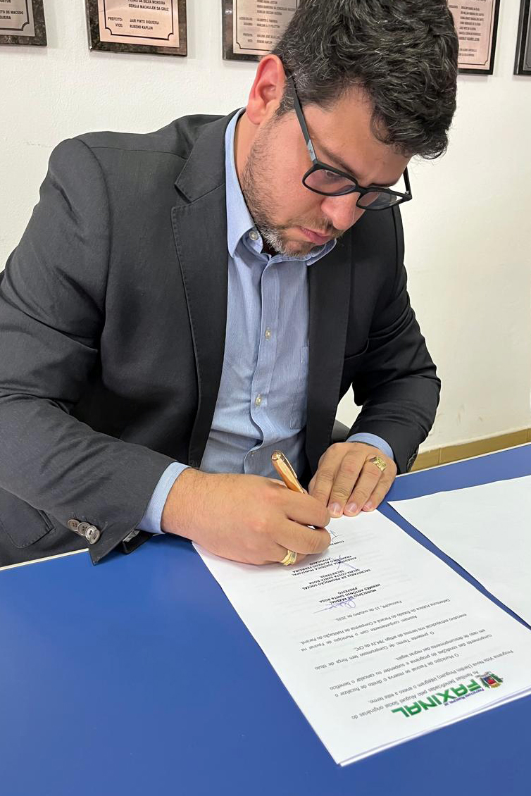 O Defensor Público João Victor Rozatti Longhi assina documento de aluguel social em Faxinal.