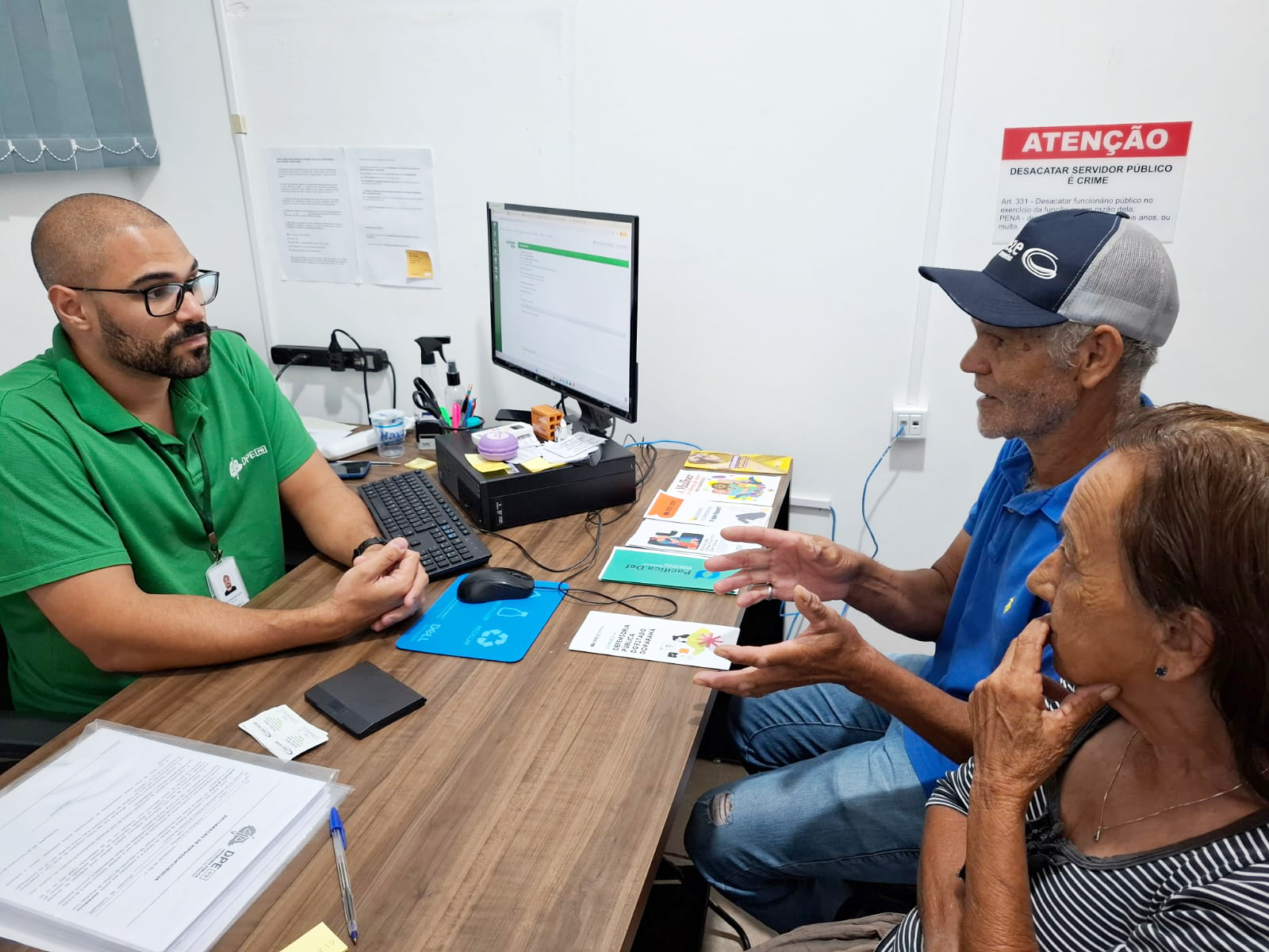 Servidor da DPE-PR atendendo casal de idosos durante mutirão do Concilia em Guaíra. 