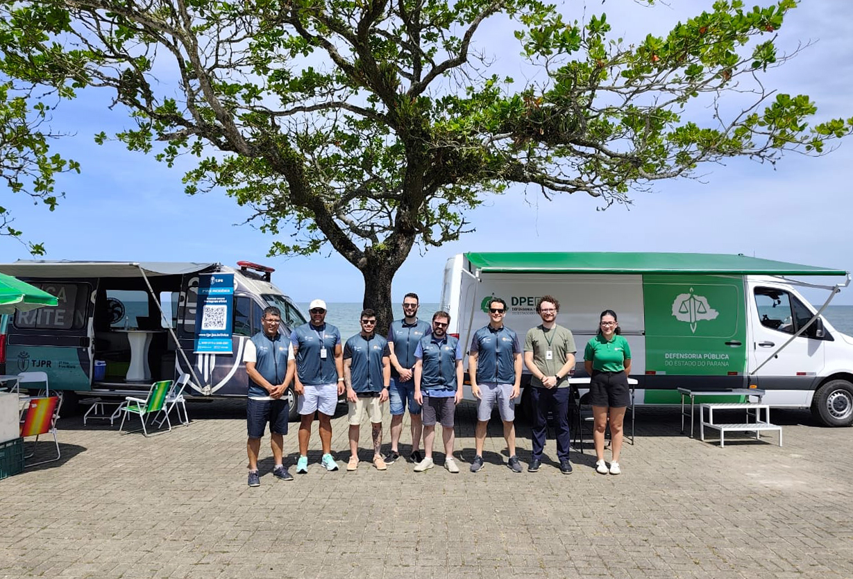 Equipe da Defensoria Pública do Paraná posa em frente à Van de Direitos durante a Operação Verão Maior em Matinhos. 