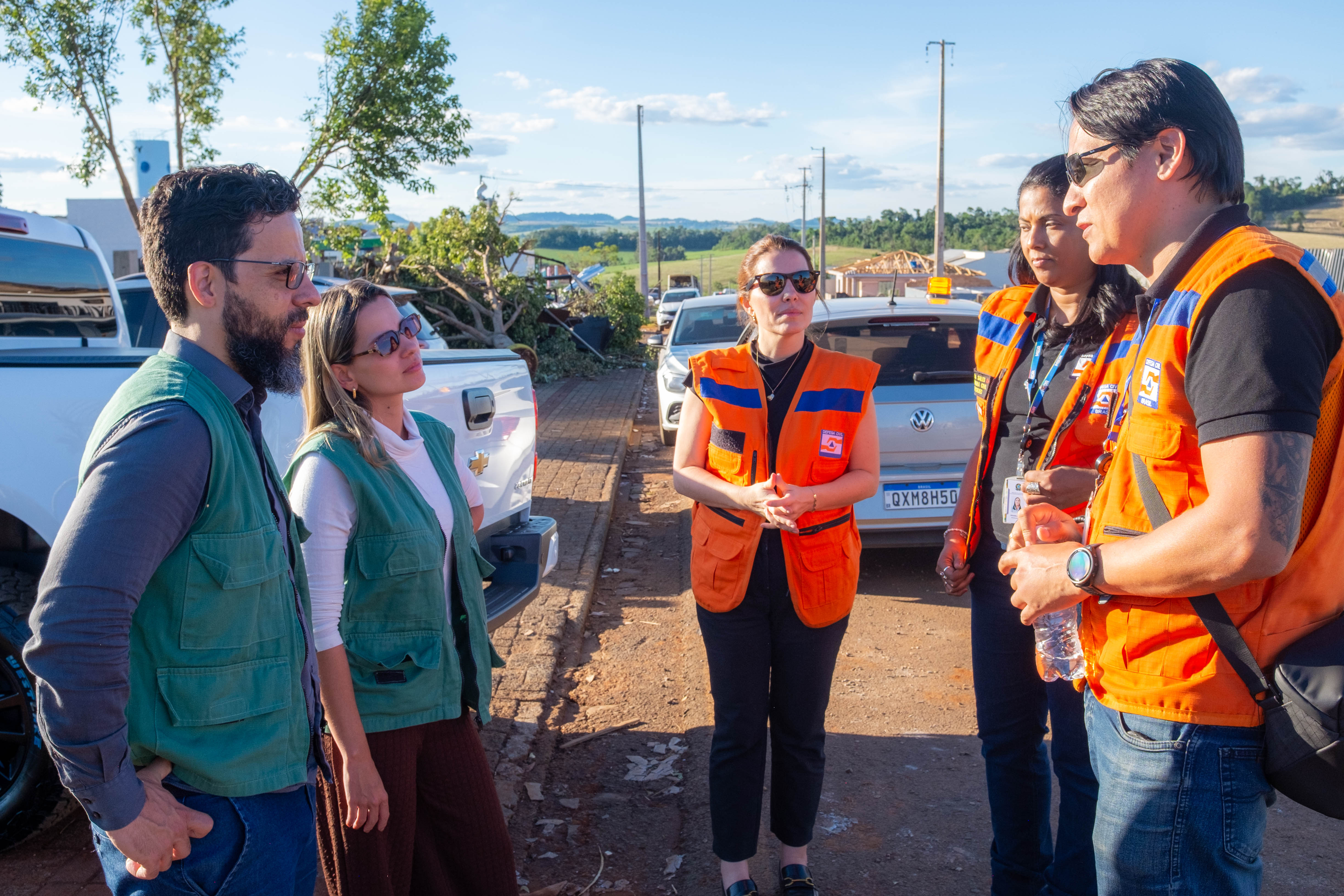 Imagem mostra a coordenadora do NUCRISE, defensora pública Ingrid Lima, conversando com as equipes da Defesa Civil do Estado. 