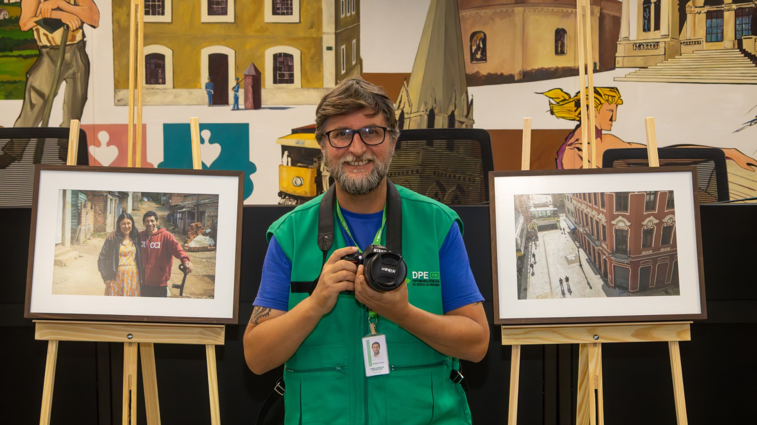 O fotógrafo Daniel Caron posa com os quadros da exposição. 