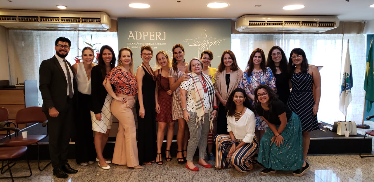Vemos todos os participantes do evento em pé, juntos, esperando a foto ser tirada.