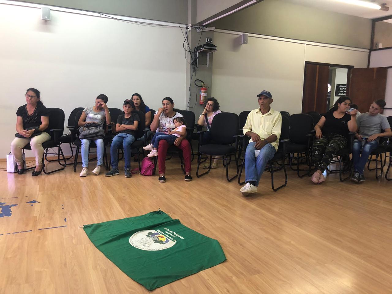 Roda do encontro com os faxinalenses, com a bandeira da comunidade estendida no meio da roda.