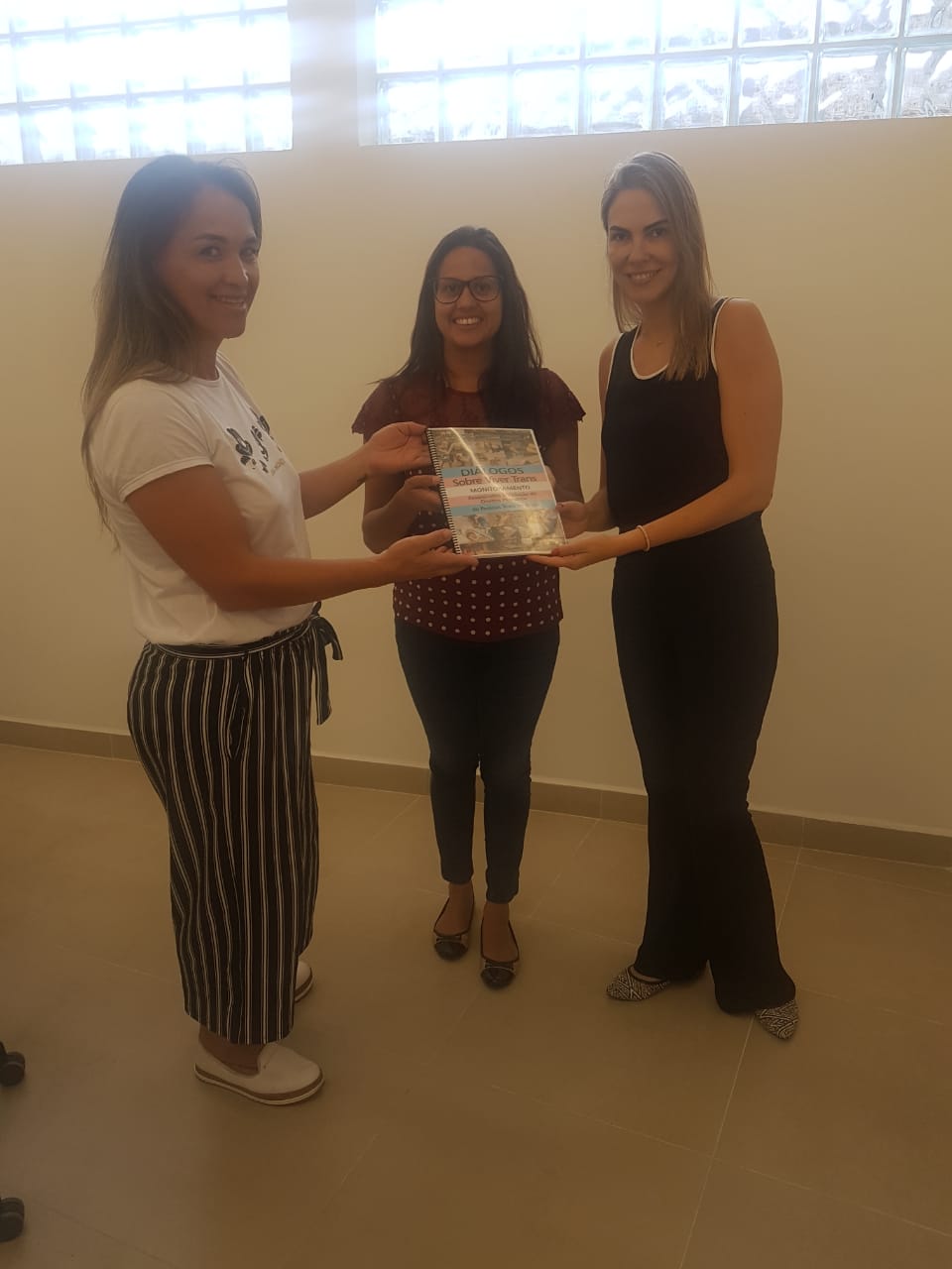 Na imagem vemos as Dras. Coordenadoras Eliana Tavares Paes Lopes e Cinthia Azevedo Santos e a presidente do Transgrupo Marcela Prado. Karollyne Nascimento segurando o documento “Diálogos Sobre Viver Trans - Monitoramento de Assassinatos e Violação de Direitos Humanos de Pessoas Trans no Brasil”.