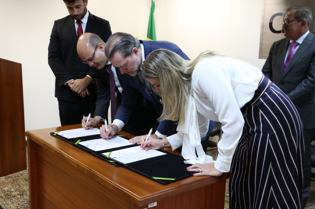 Mariana Lobo, defensora geral do Ceará no canto direito da imagem, Ministro Dias Toffoli, presidente do STF e do CNJ, no meio; e o defensor geral do Paraná, Eduardo Abraão, no canto esquerdo. Os três estão assinando o termo de cooperação.