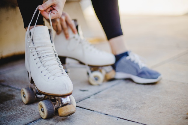 Imagem de uma menina sentada segurando laços de patins de rodas