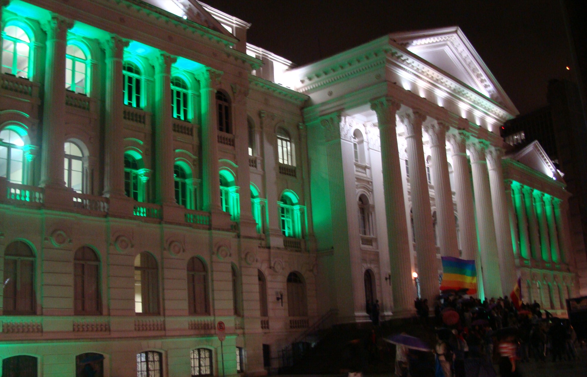 Fachada da Universidade Federal do Paraná iluminada de verde, a cor que simboliza a Defensoria Pública.
