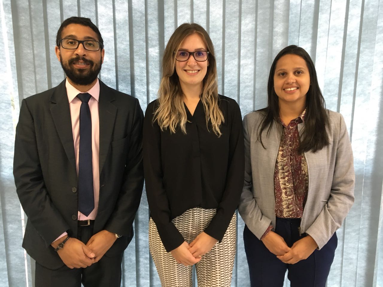 Estão na foto, da esquerda para a direita: o defensor público auxiliar do Núcleo Wisley Rodrigo dos Santos, a defensora pública de Direitos Humanos da Regional Paraná/ Santa Catarina, Carolina Balbinott Bunhak e a coordenadora do Núcleo da Cidadania e Direitos Humanos da Defensoria Pública do Paraná (NUCIDH) Cinthia Azevedo Santos. Os três estão olhando para a lente da câmera.