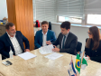 Imagem dos presentes sentados em uma mesa onde o defensor públic-geral assina alguns documentos