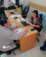 Imagem que mostra duas atendentes da Defensoria Pública. Uma delas está atendendo um homem que está com vários documentos a sua frente.