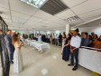 Imagem que mostra a inauguração da sala da DPE-PR no Fórum de Cambé, onde a defensora pública Aline Bastos discursa para várias pessoas que assistem a cerimônia. Todos estão em pé, em um hall amplo e bem iluminado, dentro do Fórum. Há também duas mesas no centro, com comidas e bebidas.