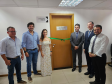 Imagem que mostra a inauguração da sala da DPE-PR no Fórum de Cambé, onde estão o prefeito de Cambé, o deputado estadual Tiago Amaral, a defensora pública Aline Bastos, o defensor-geral do Paraná, o juiz Ricardo Gorla e o representante da OAB David Garcia. Todos estão ao lado da porta da sala da Defensoria e sorriem.
