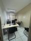 Imagem que mostra a sala de atendimento da DPE-PR em Jandaia do Sul, onde há duas mesas, com computadores com teclados e mouses, e cadeiras para quem usa o computador e para pessoas que estejam sendo atendidas. Ao fundo, há uma janela com uma cortina entreaberta. Acima, um aparelho de ar condicionado e, ao lado da janela, uma impressora multifuncional.