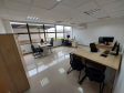 Imagem que mostra outra sala da DPE-PR no Fórum de Cambé, onde há um armário e quatro mesas com computadores e cadeiras para pessoas serem atendidas. Ao fundo é possível ver uma grande janela que mostra uma parte externa do Fórum.