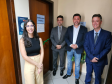 Imagem que mostra a defensora pública Maria Luiza Valverde, o defensor público-geral, André Giamberardino, e o prefeito de Jandaia do Sul, Lauro Junior, diante da porta da sala da Defensoria no Fórum de Jandaia. Na porta, há uma placa que diz “Defensoria Pública” e cruzando a porta de um lado a outro há uma fita de cetim de cor verde, com um laço ao meio. Todos sorriem.