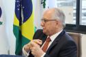 Imagem com a foto do Ministro Fachin sentado à mesa  com as bandeiras do Brasil e da Defensoria ao fundo.