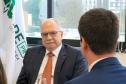 Imagem do Ministro Fachin sentado à mesa e olhando para o defensor público Matheus Munhoz, com quem estáva conversando no momento.