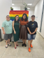 Imagem de uma foto espontânea de servidoras públicas e usuários, no fundo da imagem, dá para ver uma bandeira LGBTQIA+.