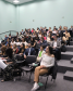 Imagem com uma foto da plateia do evento.