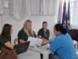 Imagem que mostra um dos atendimentos do evento. Três pessoas da Defensoria atendem uma mulher. Uma delas entrega um documento para a mulher que está sendo atendida.
