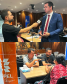 Imagem em formato de colagem entre duas fotos, a primeira, na parte de cima, uma foto de ângulo aberto mostrando o Defensor Público-Geral do Estado do Paraná, Matheus Munhoz, sendo entrevistado. Na foto de baixo, mostra dois servidores públicos conversando com uma usuária da Defensoria Pública e ao lado deles, uma pilastra contendo a logo da COPEL.
