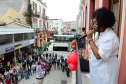Imagem da cantora Janine Mathias fazendo sua apresentação na janela do prédio histório da sede central de atendimento da Defensoria, com o público ao fundo da imagem