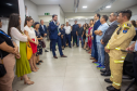 Defensor público realiza discurso em um púlpito dentro da nova sede, com banner institucional ao fundo. O público, composto por autoridades e convidados, acompanha atentamente.