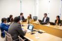 Imagem mostra um grupo de sete pessoas sentadas a mesa com laptops.