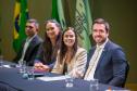 Imagem em que se vê as autoridades da DPE-PR sentadas à mesa, ao fundo as bandeiras do Paraná e do Brasil.