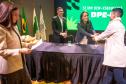 Servidor cumprimenta a autoridades na mesa da cerimônia de posse. 