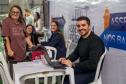 Equipe da DPE-PR posa para foto com assistidos. Quatro pessoas aparecem na foto, três sentadas e uma de pé se apoiando em muleta. 