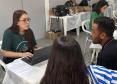 Imagem mostra servidora da DPE-PR realizando atendimento de um casal. A mulher está de costas em primeiro plano e ao fundo homem fala com a servidora. 