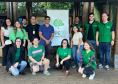 Equipe da DPE-PR posa para foto junto ao Banner da instituição. São 13 pessoas entre homens e mulheres, parte usando coletes verdes da instituição. 