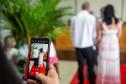 Em primeiro plano celular grava casal que está diante do juiz de paz. 
