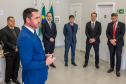 A foto foca no Defensor Público-Geral durante seu discurso, visto em primeiro plano. Com o rosto concentrado, ele gesticula e se dirige a um grupo de cinco homens que o ouvem atentamente. Os homens estão em pé, formando um semicírculo. O ambiente é uma sala ampla com paredes claras e boa iluminação.