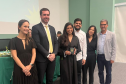 Nova defensora pública recebe sua carteira funcional ao lado de representantes da instituição e familiares. 