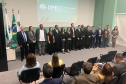 Novos defensores públicos empossados posam ao lado de representantes da instituição ao fim da cerimônia no auditório da instituição. 