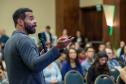 Homem negro em primeiro plano fala para uma plateia ao fundo desfocada. Palestra com especialista do Google sobre uso da Inteligência Artificial.