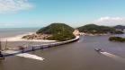 Imagem mostra a Ponte de Guaratuba e um Ferry Boat fazendo a travessia. 