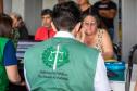 Imagem mostra Defensor Público de costas com colete da instituição realizando atendimento de uma senhora em mutirão no Litoral do Paraná.