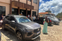 Mulher de vestido verde aparece de costas caminhando para a entrada da sede da Defensoria em Guarapuava. 