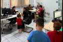 Imagem mostra mães com filhos, todos de costas, aguardando na fila para atendimento da Defensoria no Mutirão de Vagas de Creche em Guarapuava. 