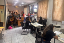 Imagem mostra várias mesas de atendimento com assistidos recebendo orientações dos servidores da Defensoria Pública do Paraná. 